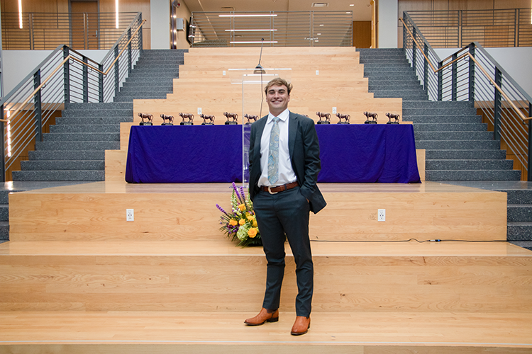Toby Trowbridge standing in front of a table with miniature tiger statue awards for Tiger Twelve recipients