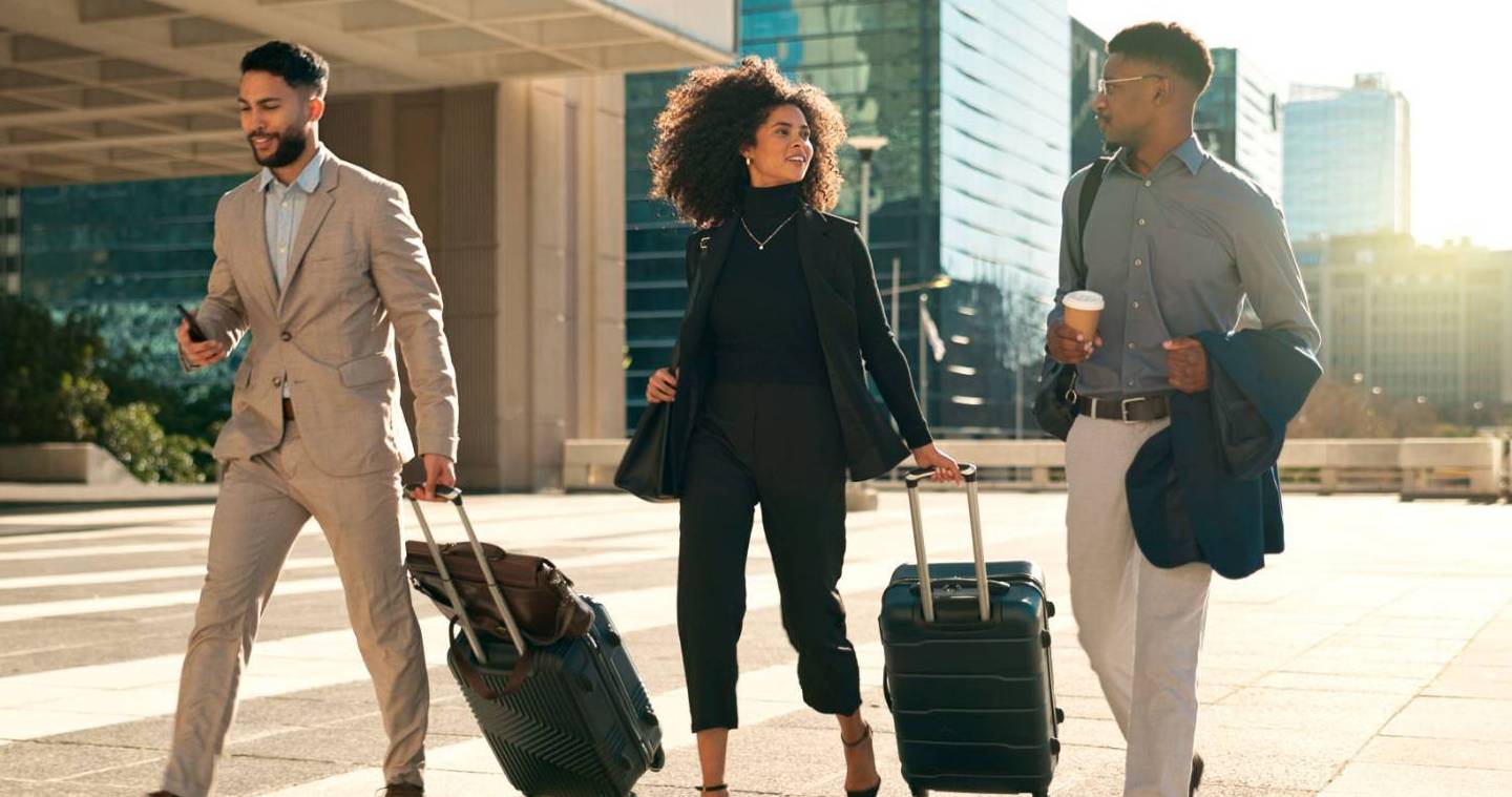 Three professionals with luggage walking and talking