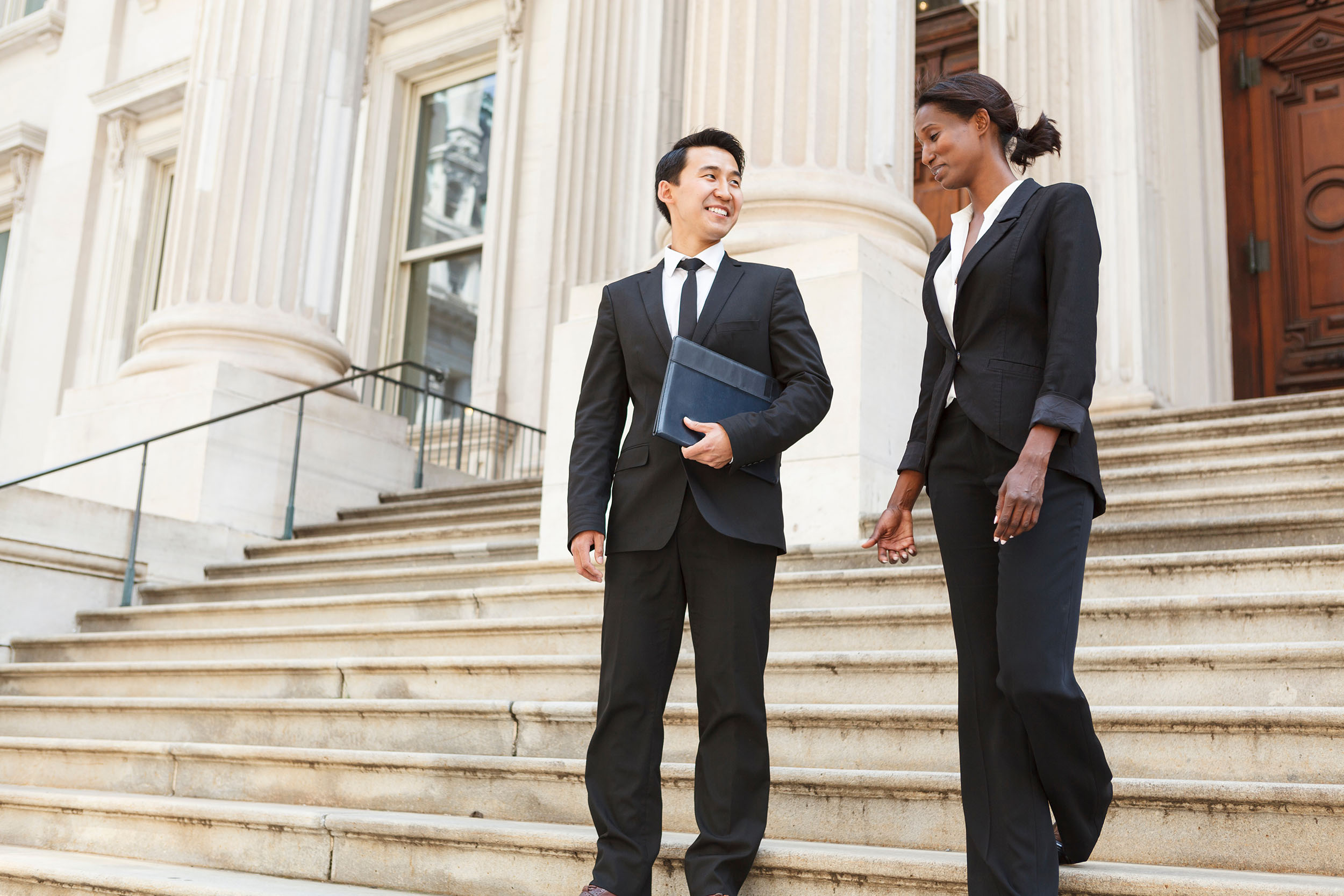 man and woman in business suits on steps of a legislative building