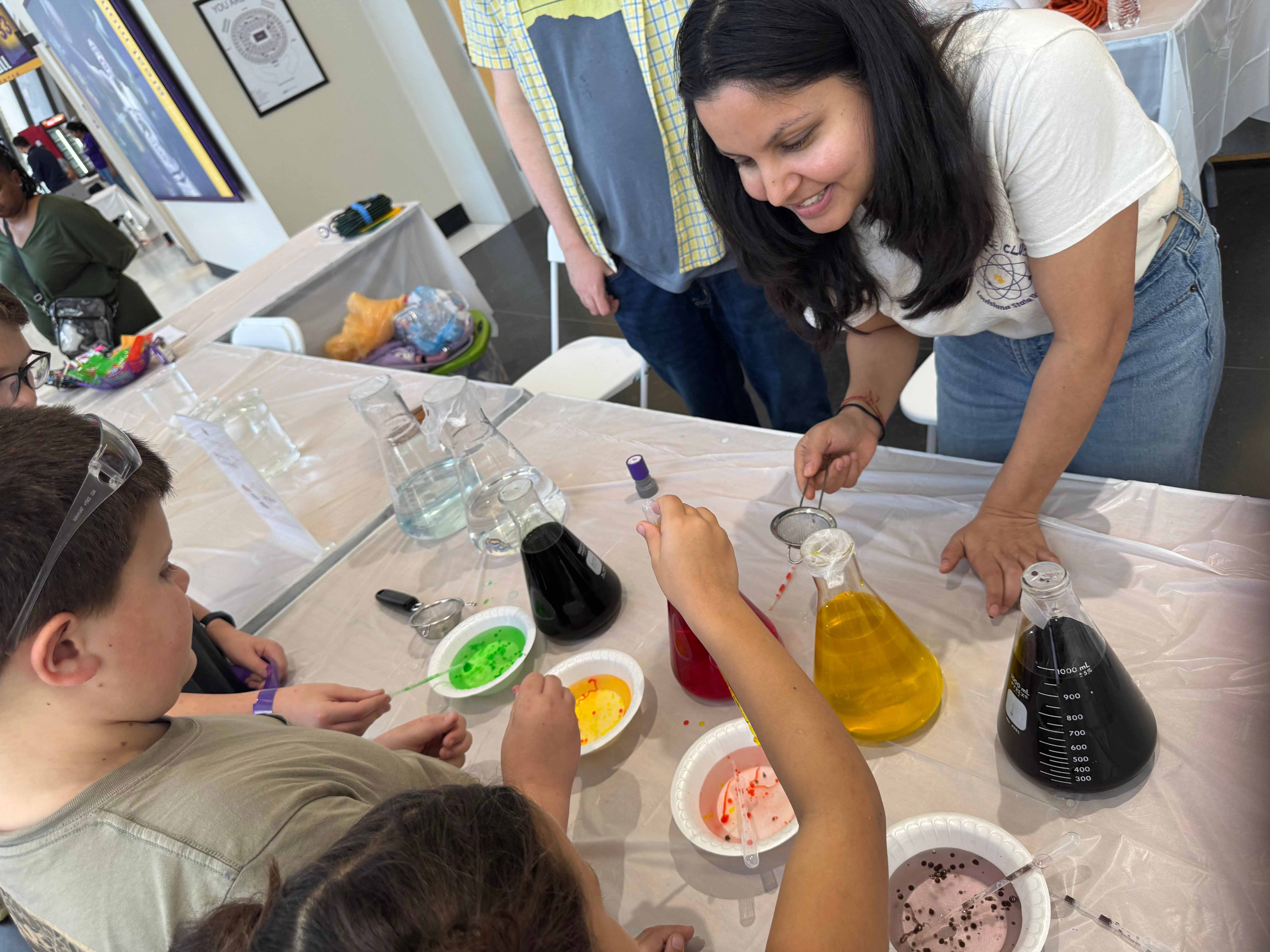 woman showing kids containers of colored liquid