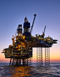 Offshore oil and gas platform at sea at sunset.